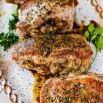 Four baked stuffed pork chops on a tray.