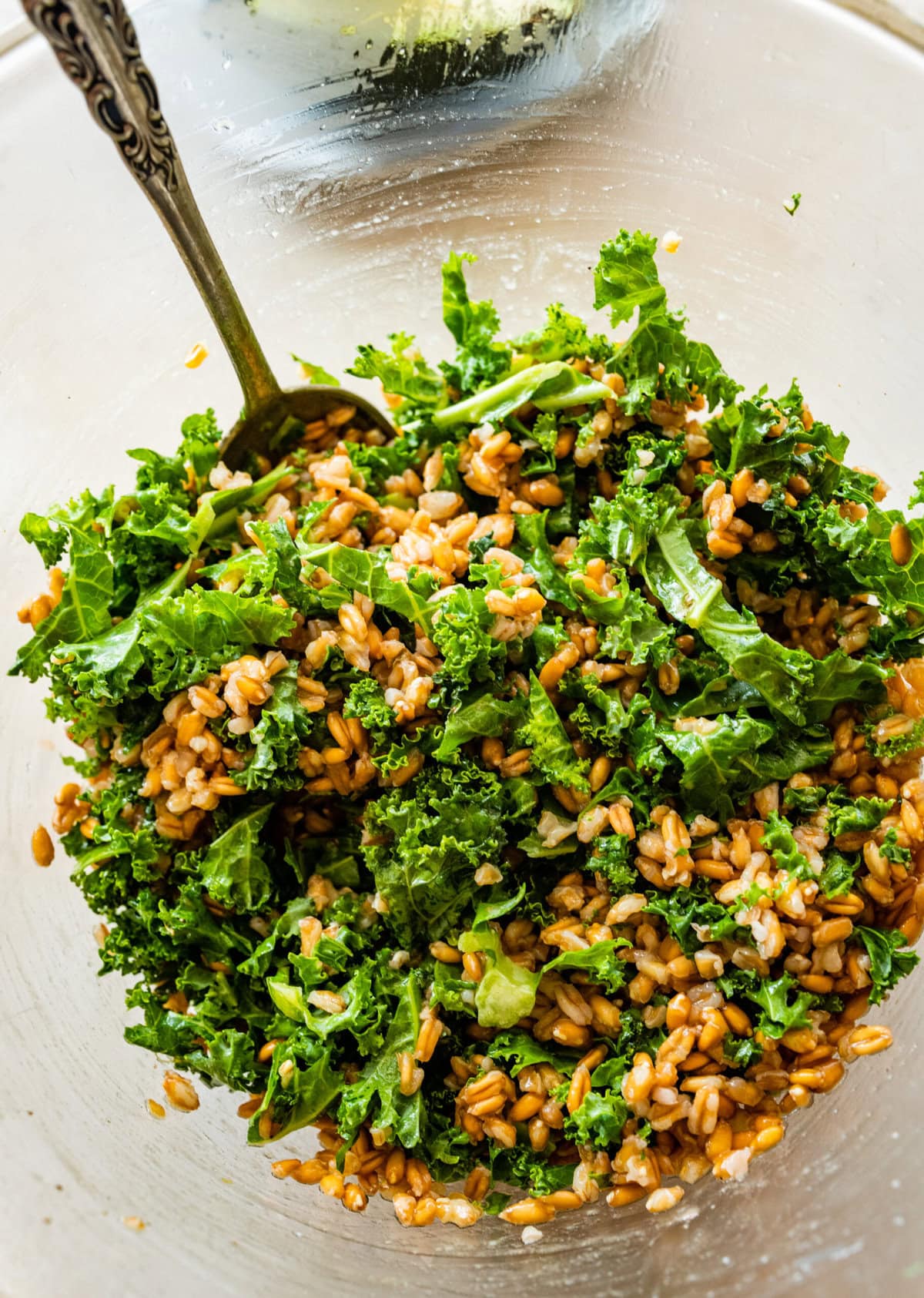How to make Roasted Veggie Grain Bowls- add grains to bowl with kale and toss.