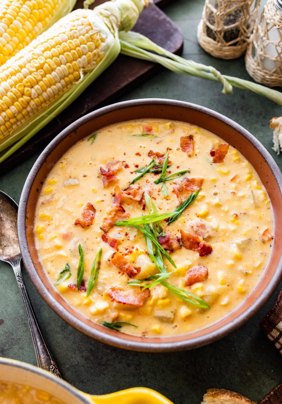 A bowl of summer corn chowder with bacon and green onions on top.
