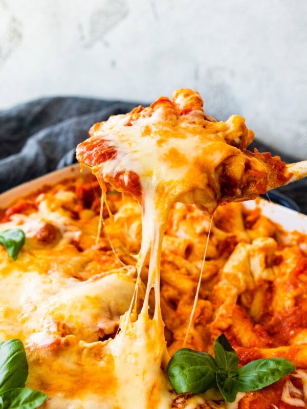 cheese pull with a wooden spoon getting a portion of the meatless baked ziti.