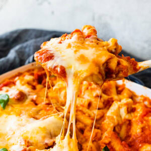 cheese pull with a wooden spoon getting a portion of the meatless baked ziti.