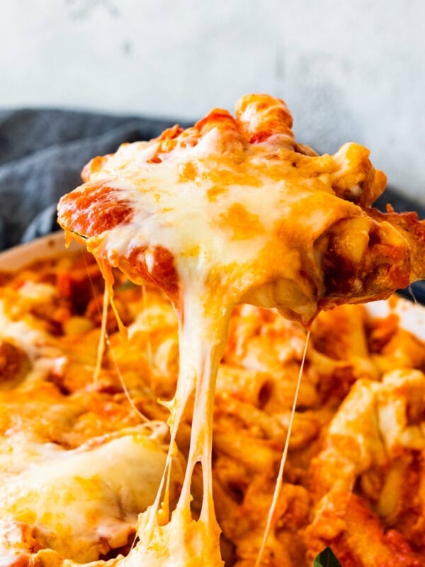 cheese pull with a wooden spoon getting a portion of the meatless baked ziti.
