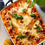 Easy meatless baked ziti recipe with golden brown top and basil leaves on top.