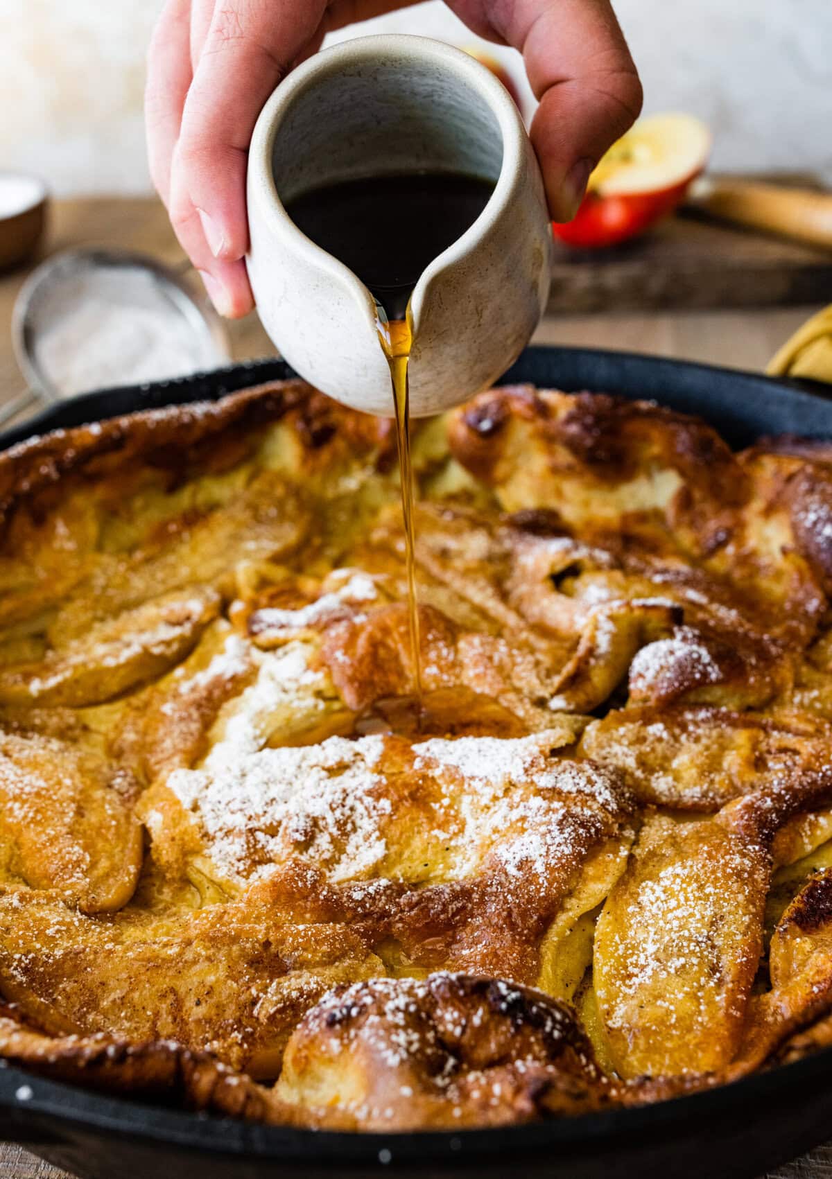 Pouring syrup over the german apple pancake.
