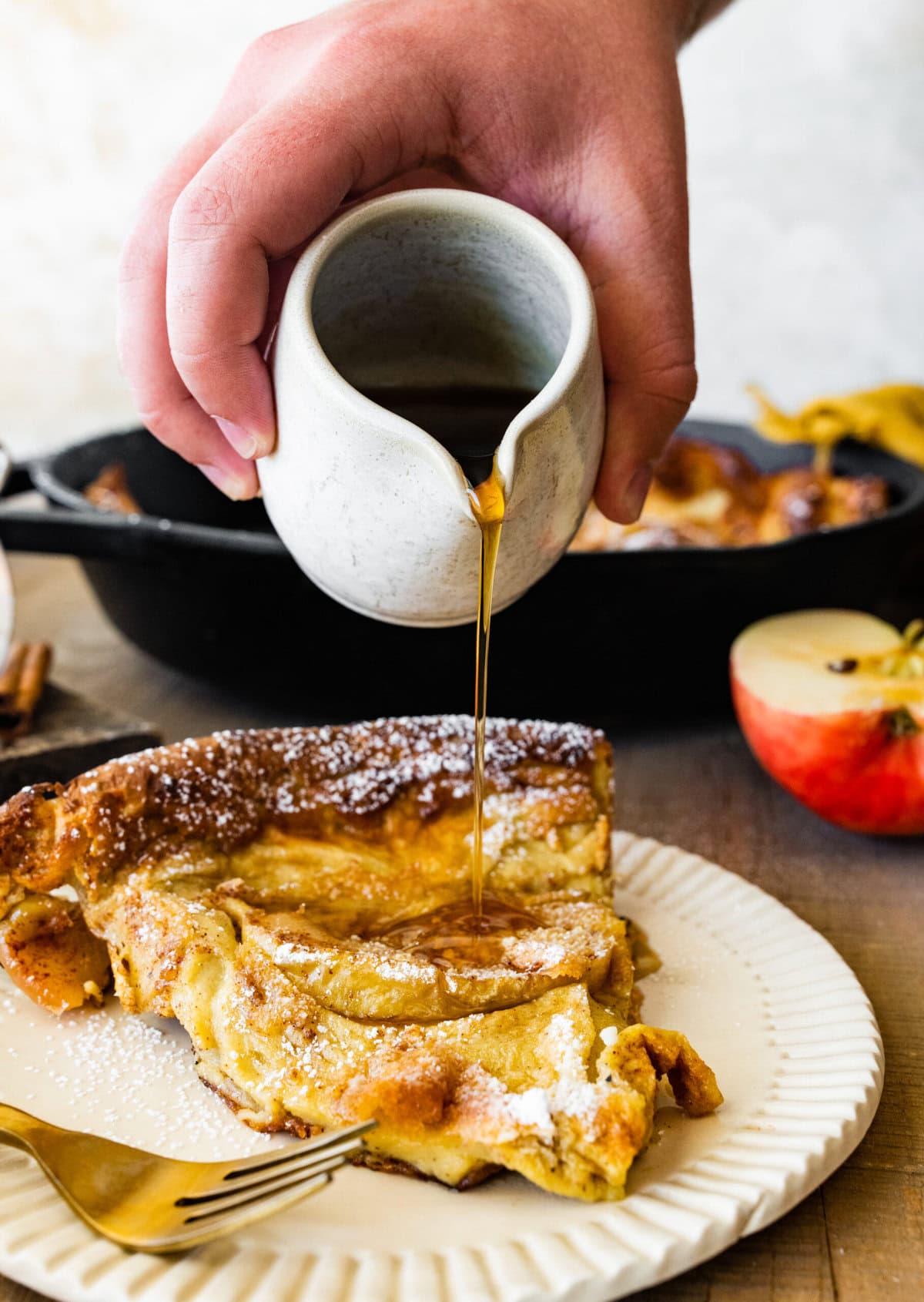 pouring syrup over a slice of the German apple pancake.