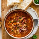 Instant Pot Navy Bean Soup with Ham Recipe in a serving bowl with parsley and bread on the side.
