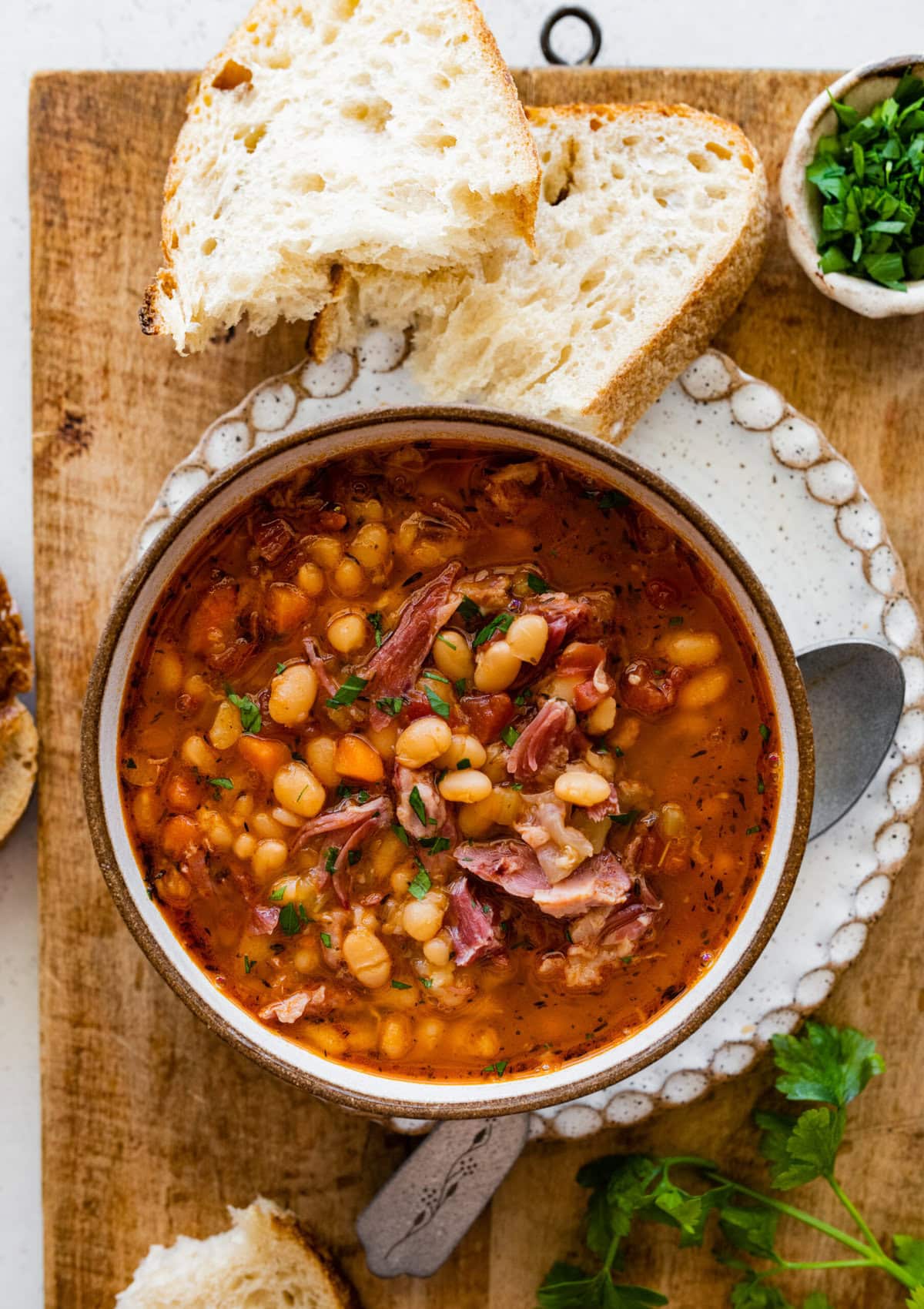 Instant Pot Navy Bean Soup with Ham Recipe in a serving bowl with parsley and bread on the side.