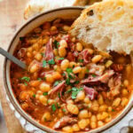 Instant Pot Navy Bean Soup with Ham Recipe in a bowl with a piece of bread in it.