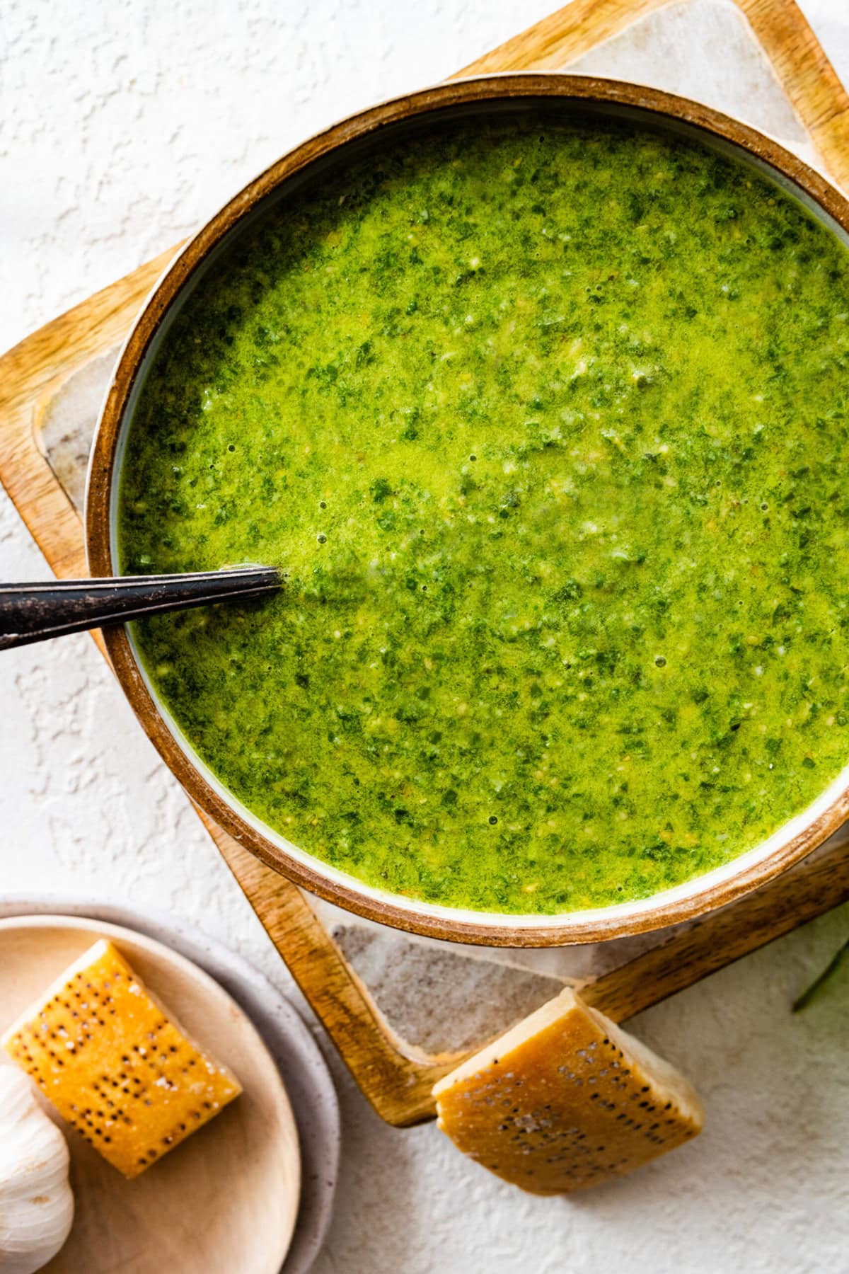 spoonful of Best Authentic Pesto Genovese (Basil Pesto) over the bowl of fresh pesto. Parmigiano on the side.