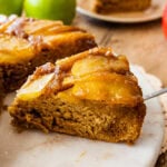 Caramel Apple Upside Down Cake Recipe on a platter. The caramel apple layer is visible on the top. Slice of cake on a cake server.