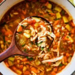 Easy Mexican chicken soup recipe with a large wooden spoon taking a serving.