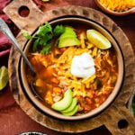 Easy Mexican chicken soup in a bowl with all the toppings on it and a spoon in it ready to eat.