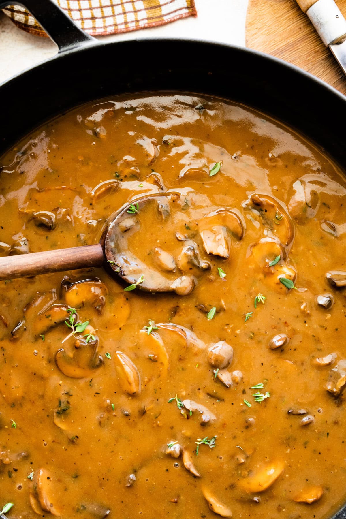 Easy mushroom gravy in a skillet pan with wooden spoon.