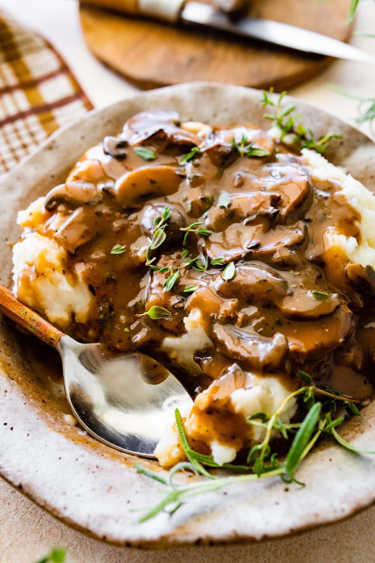 Easy mushroom gravy served over mashed potatoes and some herbs over the top. A spoon in the bowl to eat it.