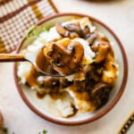 Easy mushroom gravy served over mashed potatoes and some herbs over the top. Spoon holding up a bite.