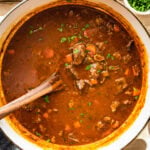 cooked soup with wooden ladle holding a portion of the soup ready to serve.