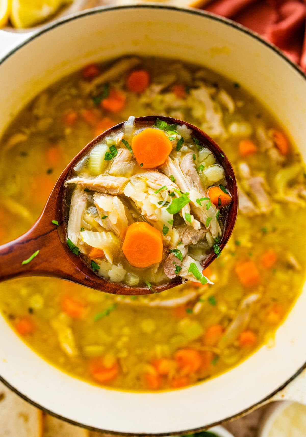 A ladle full of leftover turkey soup held up over the pot.
