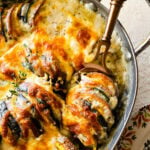 Beautiful vegetable au gratin in an oval baker with a cheese brown top. Spoon taking out a portion of the finished creamy vegetables.