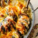 Spoon scooping vegetable au gratin from a pan.