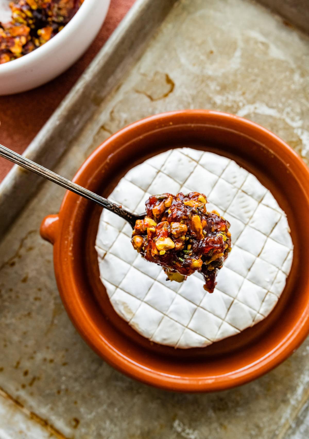 How to make baked brie recipe step-by-step instructions: add the topping to the scored brie.