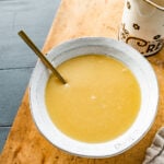 How to make creamy vanilla sauce step-by-step: finished sauce in a rustic bowl with spoon in it.