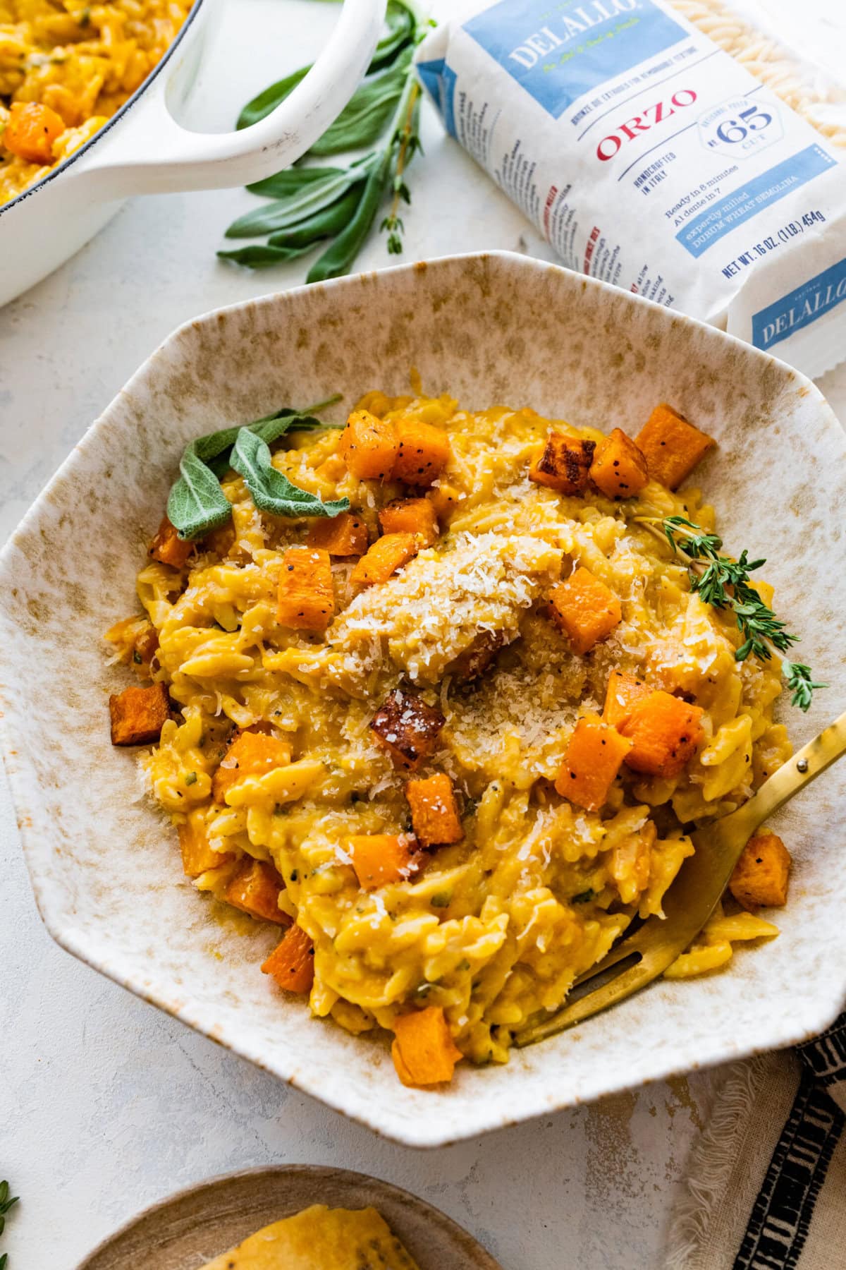 Bowl of the finished butternut squash orzo with a fork ready to eat.