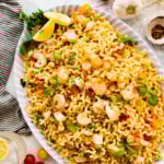 Lobster pasta recipe on a large serving platter with lemon wedges on the side and the basil leaves on top.