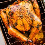 How to make a Thanksgiving turkey recipe step-by-step: turkey in the roasting pan after it is baked. It is golden brown with herbs on top.