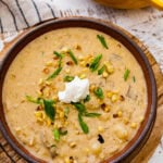 bowl of potato corn chowder recipe with sour cream and green onions on top ready to eat.