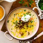 Bowl full of sausage and potato soup with extra cheese and sausage on top with a dollop of sour cream.