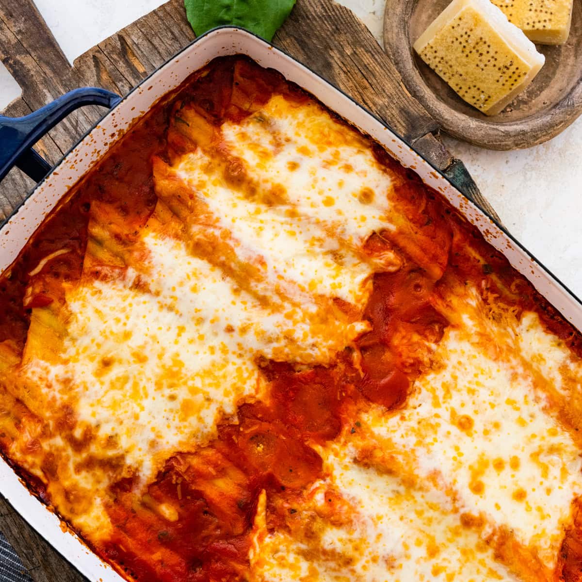Baked Spinach and ricotta manicotti in a beautiful casserole dish. Fresh parmigiano cheese on the side.