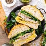 porchetta sandwich with Italian Salsa Verde on the side. The sandwiches are on a metal serving platter.