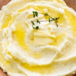 Serve the mashed potatoes in a serving plate with a little butter on top and sprig of thyme, if desired. Close up of the mashed potatoes dish.