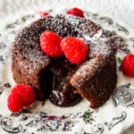 Serve the chocolate lava cakes on a plate with berries, if desired. A bite taken out of the lava cakes and the molten center is spilling out onto the plate.