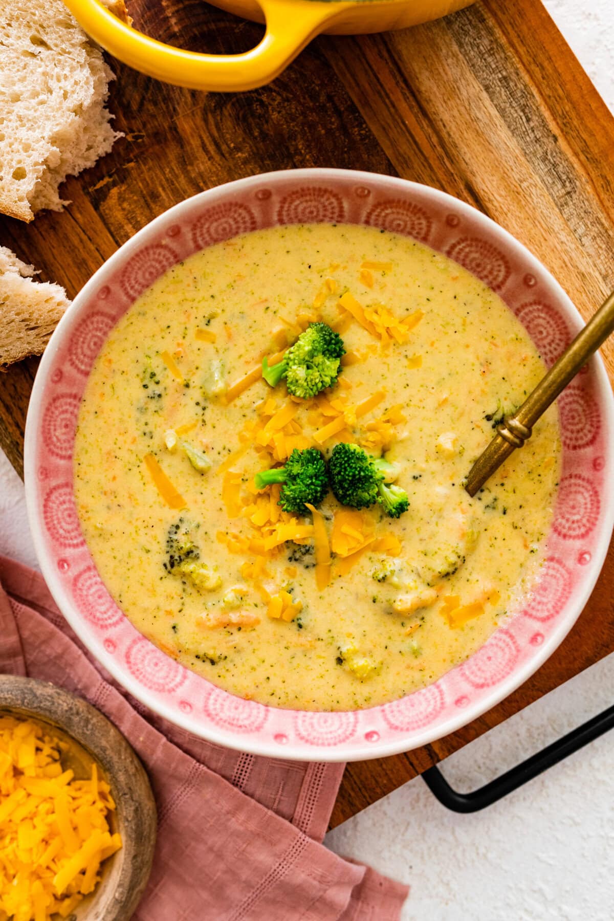 Broccoli cheddar soup recipe in a pink bowl with a spoon in it ready to serve.