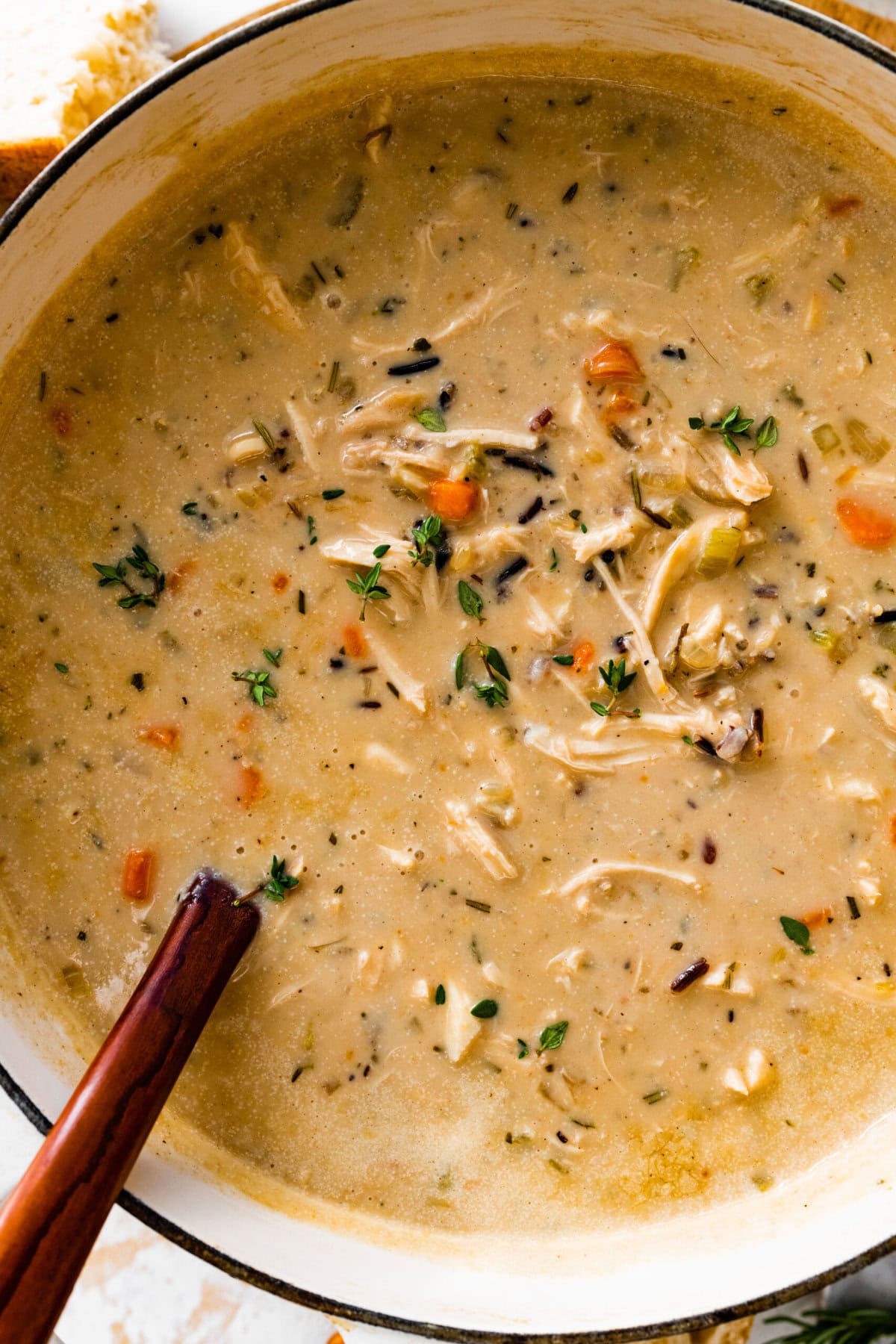 Creamy Chicken Wild Rice Soup Recipe in a soup pot with a wooden ladle in it.