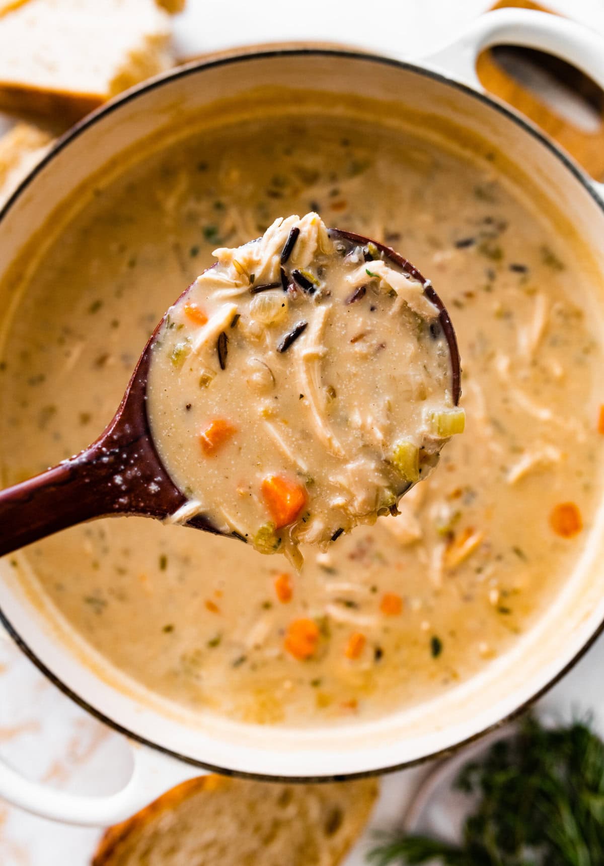 Creamy Chicken Wild Rice Soup Recipe in a soup pot with a wooden ladle in it.