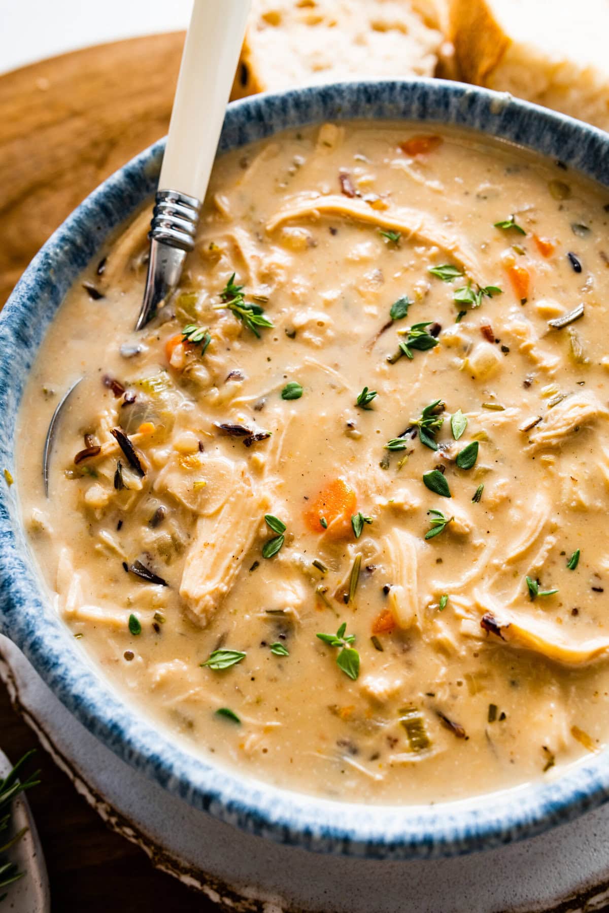 Creamy Chicken Wild Rice Soup Recipe in a soup bowl with crusty bread on the side ready to serve. Spoon in the bowl ready to eat.