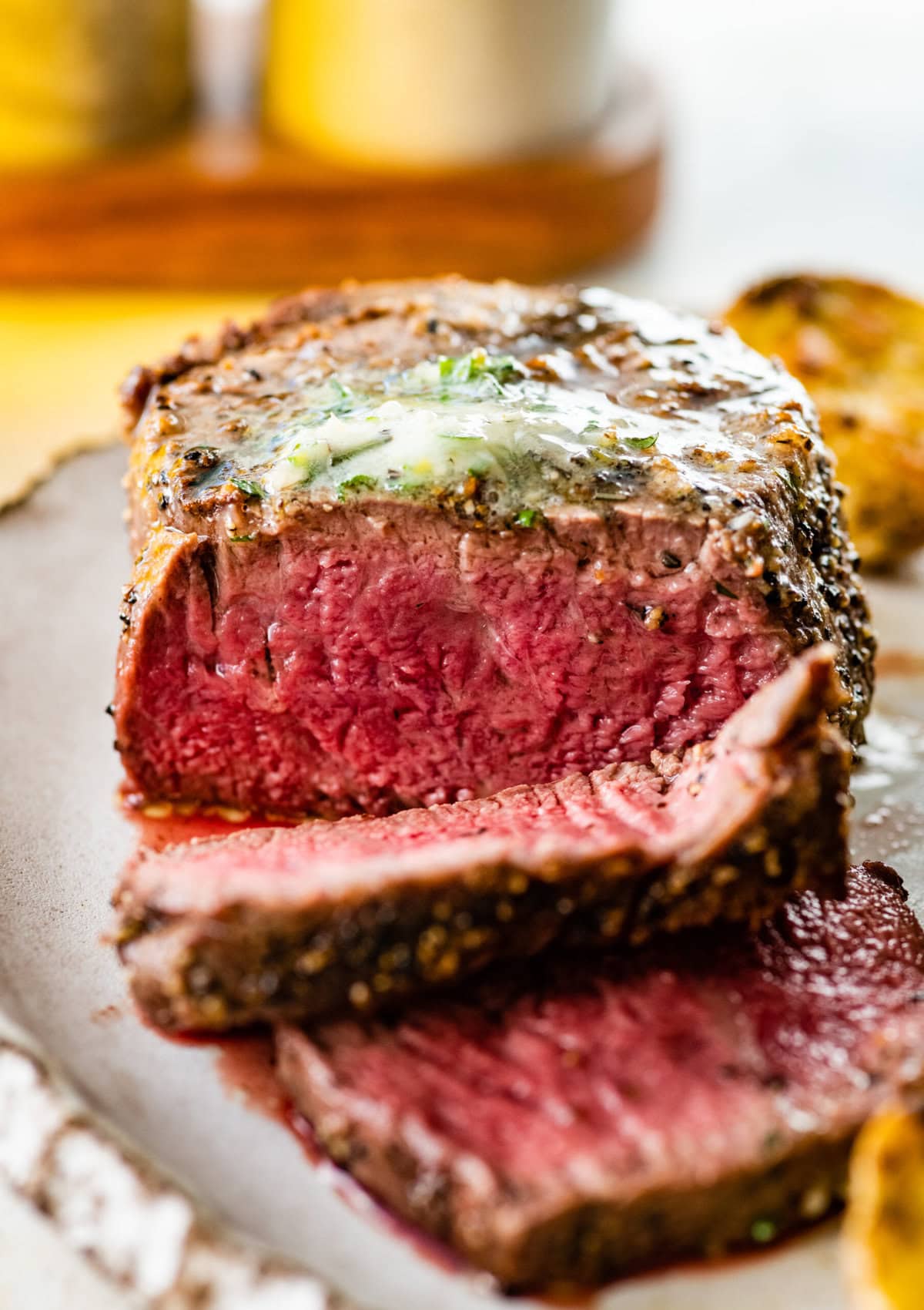 Close up of grilled filet mignon sliced with the herb butter on top.