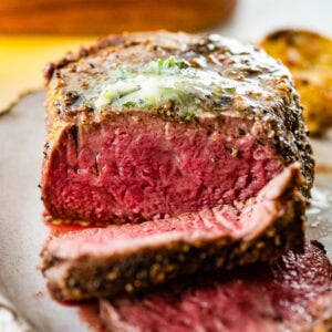 Close up of grilled filet mignon sliced with the herb butter on top.