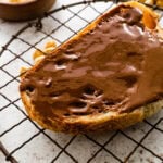 A piece of sourdough toast with homemade Nutella on it ready to eat.
