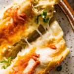 two white chicken enchiladas on a plate with cheese pull ready to eat.