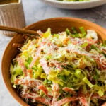 Famous La Scala chopped salad in a small wooden serving bowl with a fork. Extra dressing on the side.