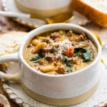 bowl of hot soup in a white soup mug with cheese on top.