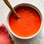 strawberry coulis in a bowl with a spoon in it.