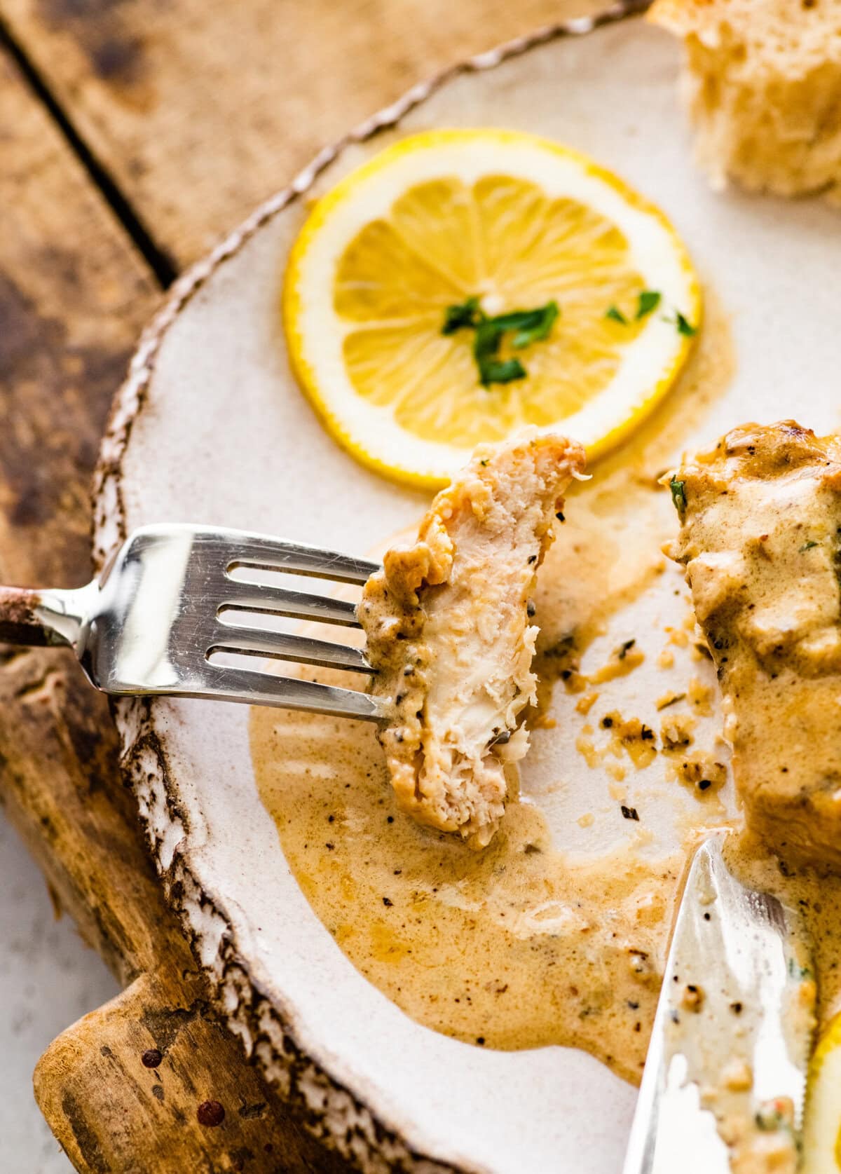 A bite taken out of the cream lemon chicken on a fork.