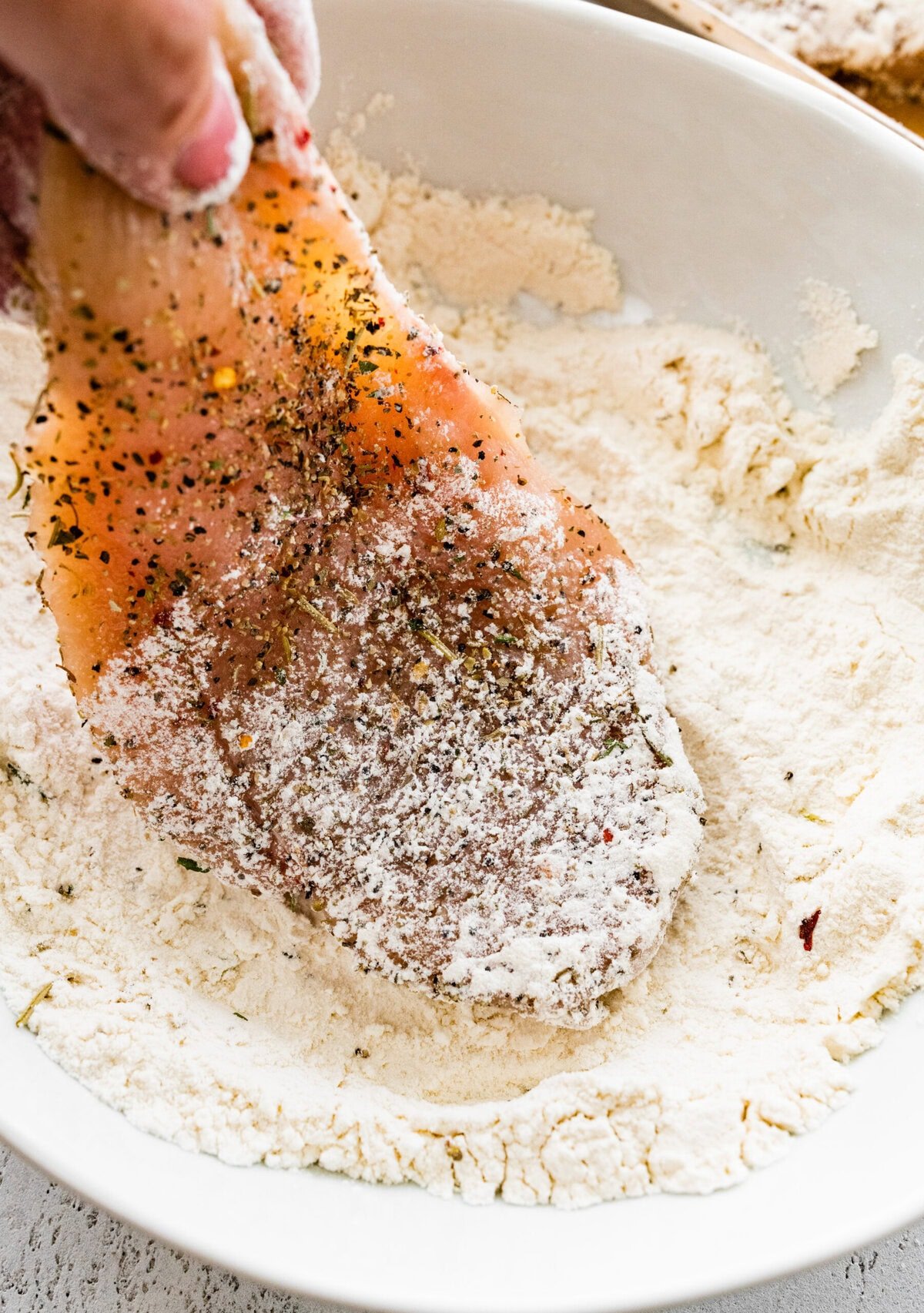 First, season the chicken and dredge in flour.