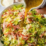 pouring the parmesan vinaigrette over the La Scala Chopped salad.