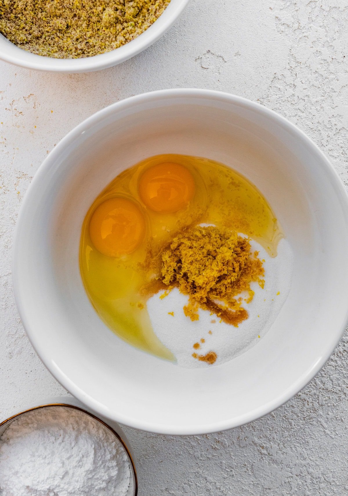 Making Italian Pistachio Cookies- Add the eggs, sugar, lemon zest, and sugar in a bowl.