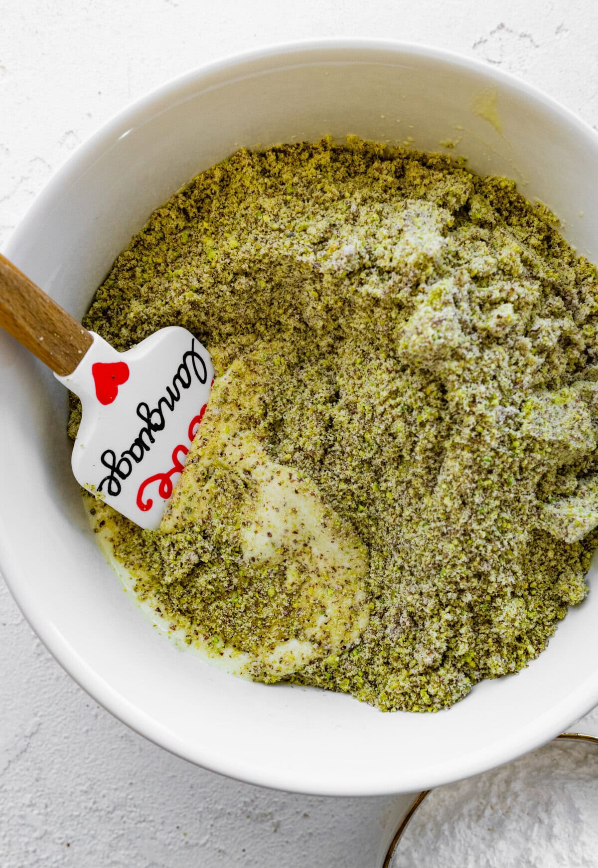 Making Italian Pistachio Cookies- mix the ground pistachios and almond flour in a bowl with a spatula.